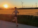 Eine Frau die gerade bei Sonnenuntergang läuft, im Hintergrund ist ein Feld zu sehen