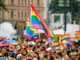 Regenbogenfahne die in einer großen Menschenmenge in die Luftgehalten wird, Vienna Pride in Wien, viele Menschen an der Regenbogenparade